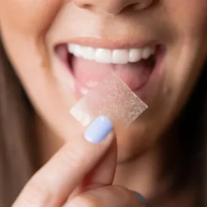 Woman holding dissolvable strip near mouth.