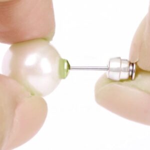 Close-up of hands holding a pearl earring.