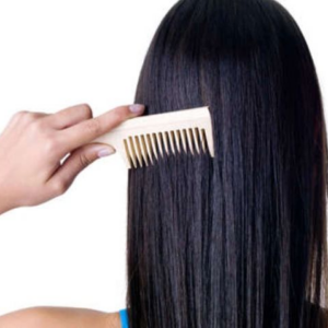 Person combing long, straight, black hair with a wooden comb.