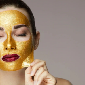 Woman with a gold facial mask relaxing with eyes closed.
